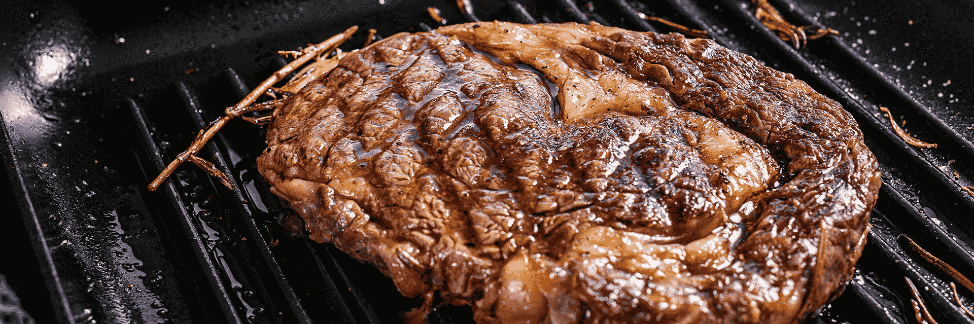 Premium grilled Ribeye Steak with fresh rosemary and rich marbling available at Roatan Provision